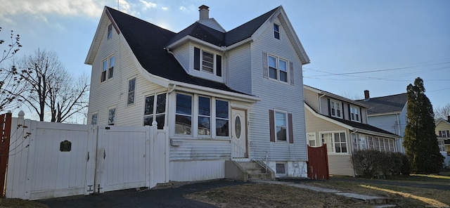 view of front of property with entry steps, a chimney, a gate, and fence