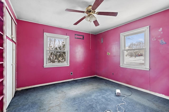 empty room with ceiling fan and dark colored carpet