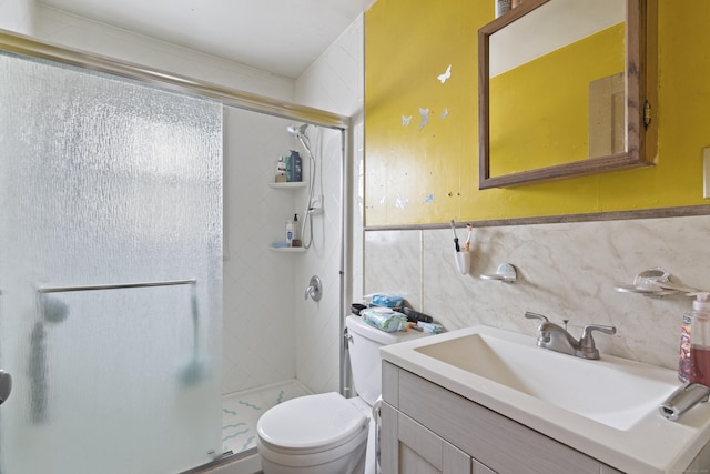 bathroom with a shower with shower door, tile walls, toilet, and vanity