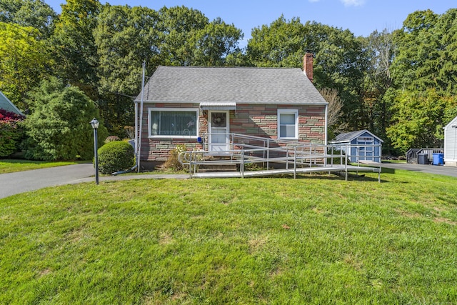 view of front of house with a storage unit and a front yard