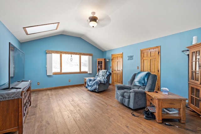 sitting room featuring ceiling fan, vaulted ceiling with skylight, and light hardwood / wood-style flooring