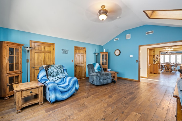 sitting room with ceiling fan, lofted ceiling with skylight, and hardwood / wood-style flooring