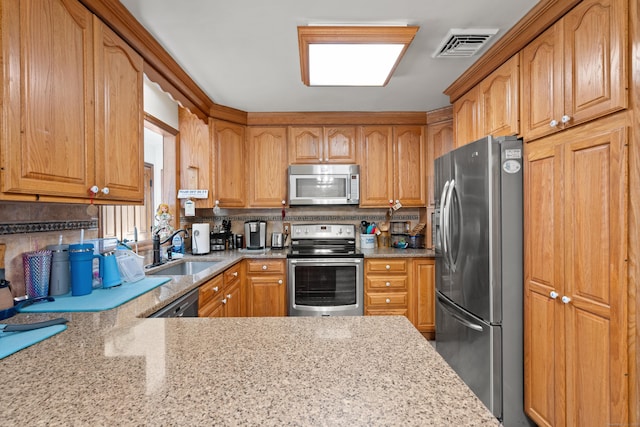 kitchen featuring light stone countertops, appliances with stainless steel finishes, tasteful backsplash, and sink