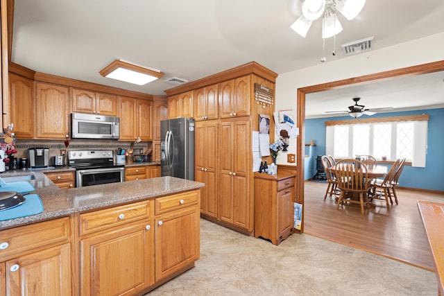 kitchen with tasteful backsplash, ceiling fan, light hardwood / wood-style floors, kitchen peninsula, and appliances with stainless steel finishes