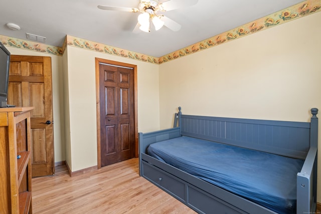 bedroom with ceiling fan, light hardwood / wood-style floors, and a closet