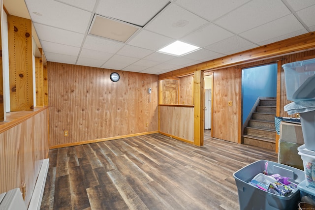 basement with hardwood / wood-style floors, a drop ceiling, and wooden walls