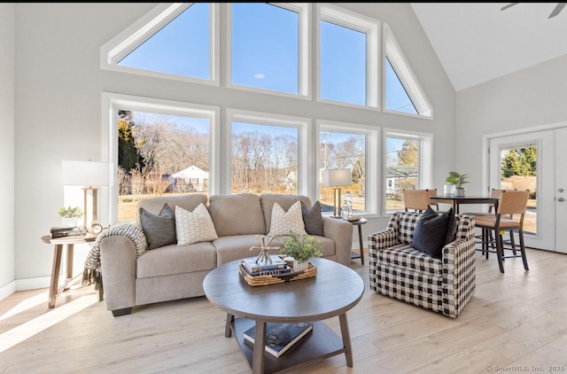 living room with light wood-type flooring, french doors, and high vaulted ceiling