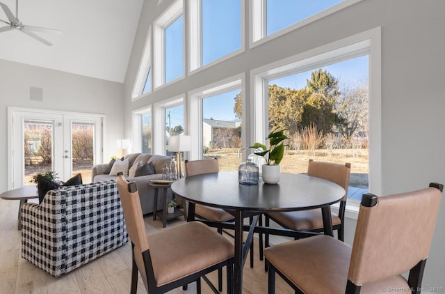 dining area with ceiling fan, light hardwood / wood-style flooring, french doors, and high vaulted ceiling