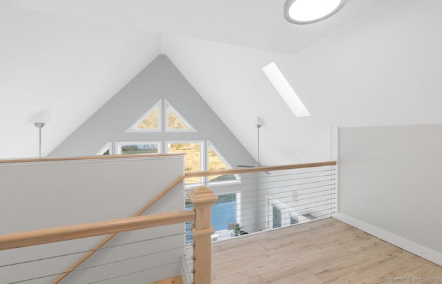 staircase featuring vaulted ceiling with skylight and hardwood / wood-style floors