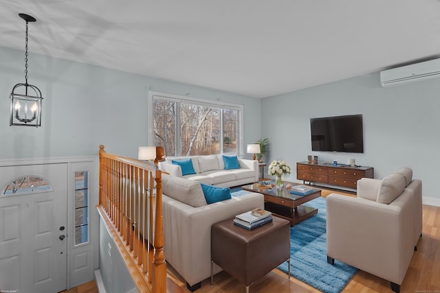 living room with an inviting chandelier, a wall mounted AC, and light hardwood / wood-style flooring