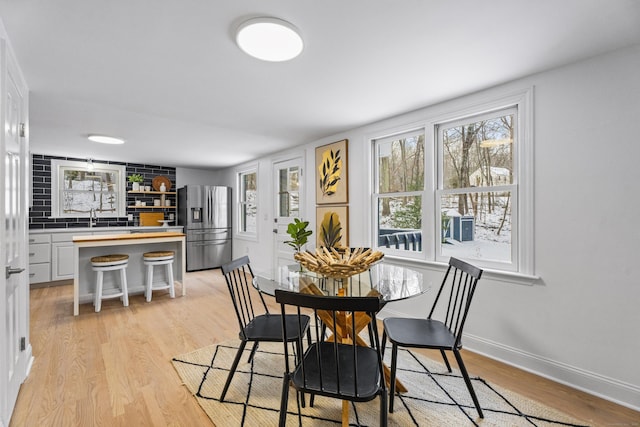 dining area featuring a healthy amount of sunlight, sink, and light hardwood / wood-style flooring