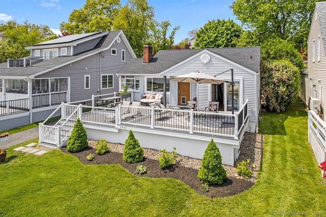 rear view of property featuring a wooden deck and a lawn