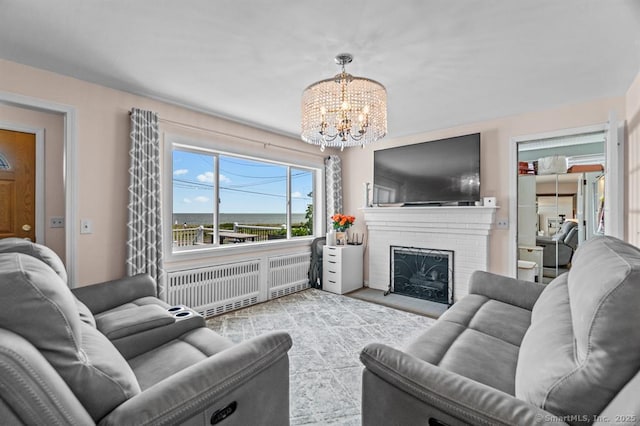 living room featuring radiator, a fireplace, and an inviting chandelier