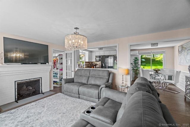 living room with dark wood-type flooring, an inviting chandelier, and a fireplace