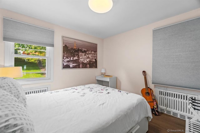 bedroom with dark hardwood / wood-style flooring and radiator heating unit