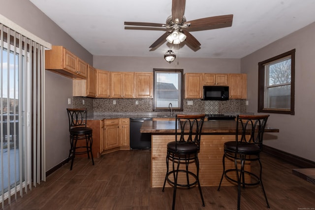 kitchen featuring black appliances, dark hardwood / wood-style floors, sink, ceiling fan, and a breakfast bar area