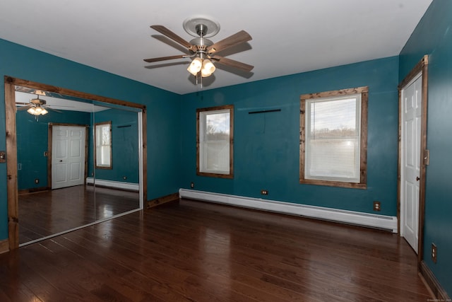 unfurnished bedroom with ceiling fan, a baseboard heating unit, and dark hardwood / wood-style floors