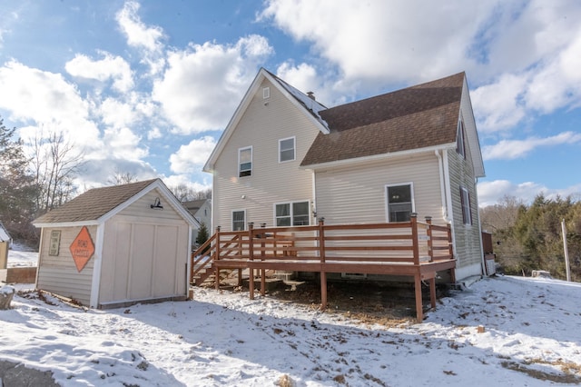 snow covered house with a wooden deck and a shed