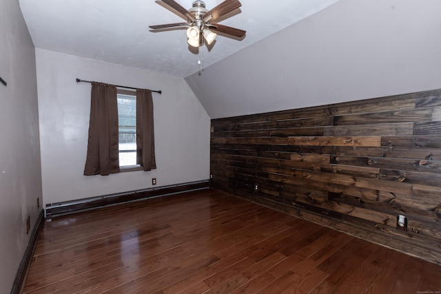 additional living space featuring a baseboard radiator, lofted ceiling, dark wood-type flooring, wood walls, and ceiling fan