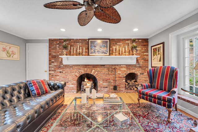 living room with a brick fireplace, hardwood / wood-style floors, ornamental molding, and ceiling fan