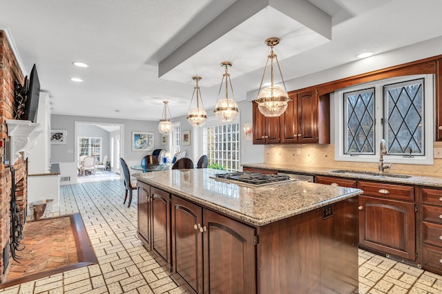 kitchen with a kitchen island, decorative backsplash, sink, hanging light fixtures, and a brick fireplace