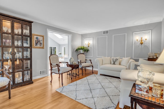 living room with a skylight, crown molding, and hardwood / wood-style flooring