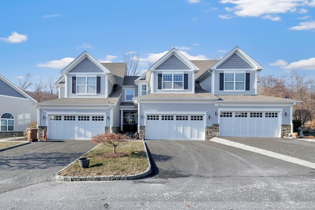 view of front of property featuring a garage, stone siding, and driveway