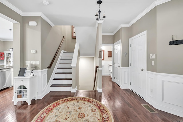 entrance foyer with crown molding, wainscoting, visible vents, and dark wood finished floors