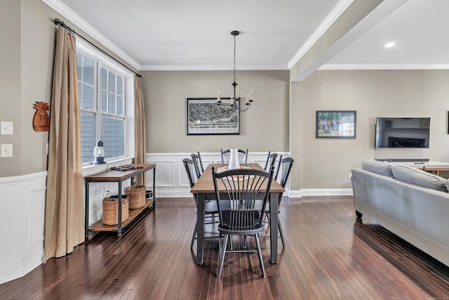 dining area with dark wood-style floors, an inviting chandelier, crown molding, and wainscoting