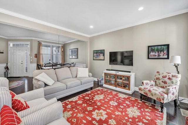 living area featuring ornamental molding, wainscoting, wood finished floors, and an inviting chandelier