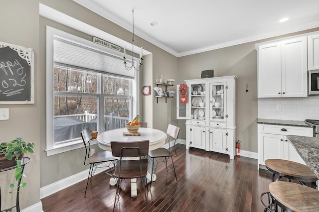 dining room featuring crown molding, dark wood-type flooring, and baseboards