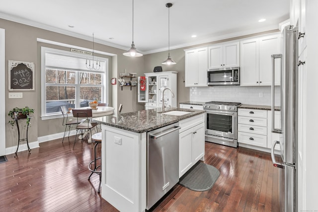 kitchen featuring stainless steel appliances, backsplash, white cabinetry, a sink, and dark stone countertops