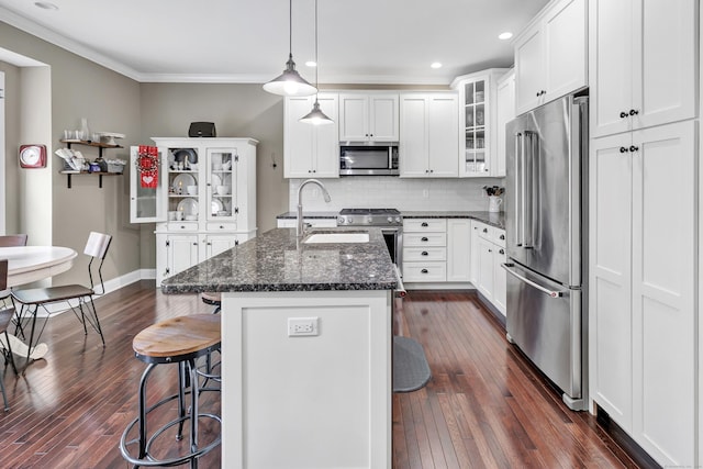 kitchen with a sink, a kitchen breakfast bar, appliances with stainless steel finishes, ornamental molding, and backsplash