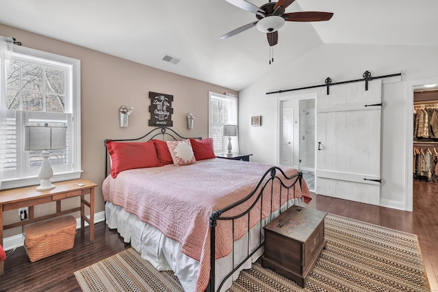 bedroom with lofted ceiling, a barn door, wood finished floors, visible vents, and a spacious closet