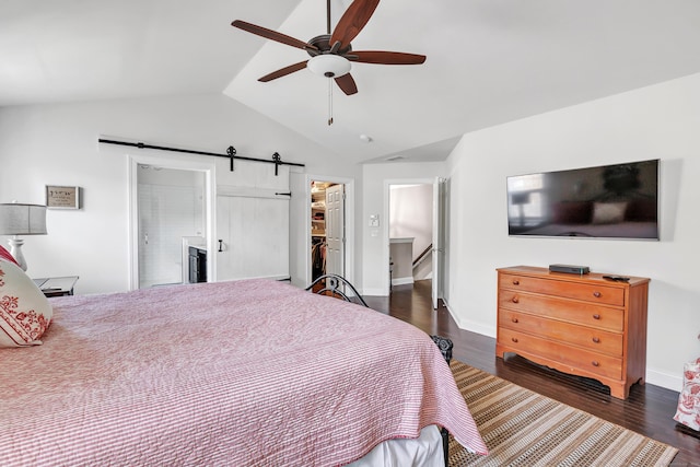 bedroom featuring lofted ceiling, a barn door, wood finished floors, a closet, and a walk in closet