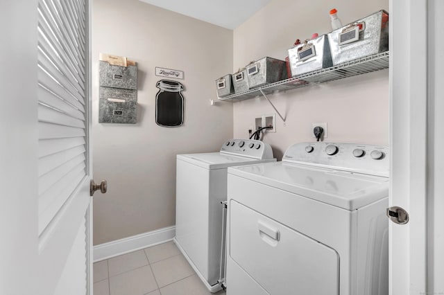 laundry area featuring laundry area, baseboards, light tile patterned flooring, and independent washer and dryer