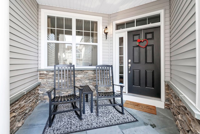 property entrance featuring stone siding and covered porch