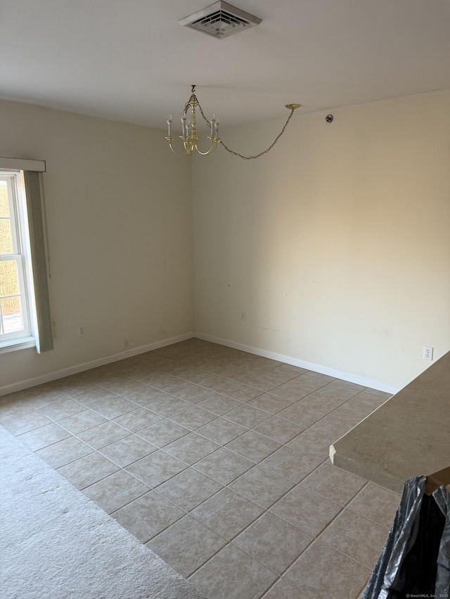 unfurnished room with an inviting chandelier and light tile patterned floors