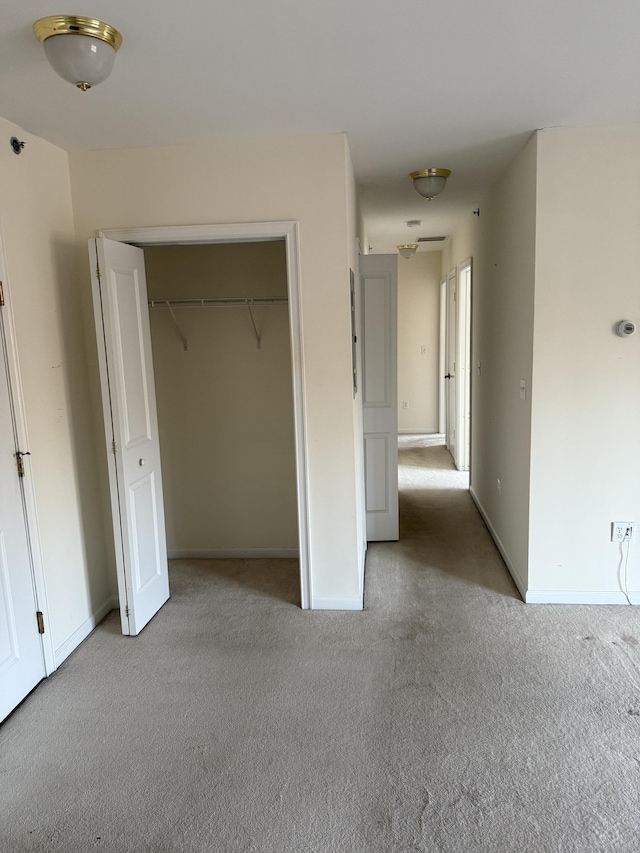 unfurnished bedroom with light colored carpet and a closet