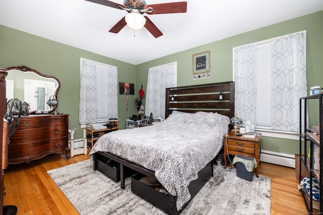 bedroom featuring ceiling fan, baseboard heating, and hardwood / wood-style flooring