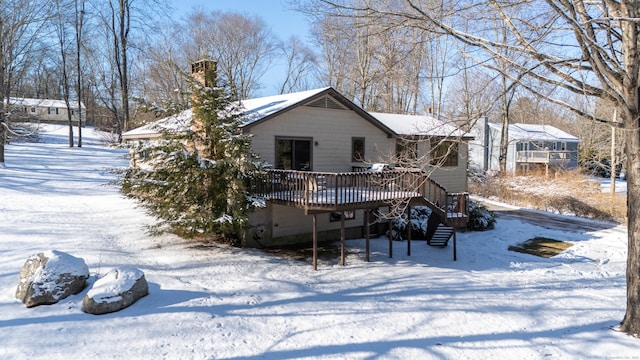 snow covered back of property featuring a wooden deck