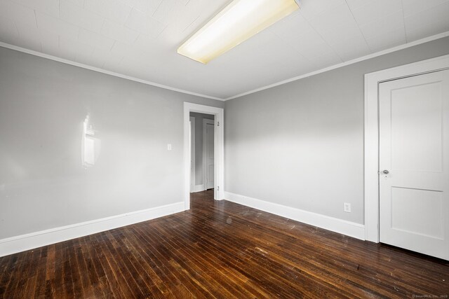 spare room with dark hardwood / wood-style floors and crown molding