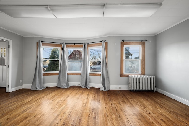 empty room featuring hardwood / wood-style flooring, plenty of natural light, crown molding, and radiator