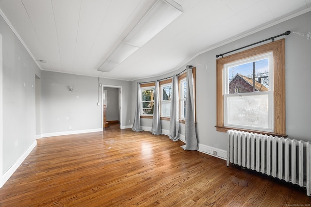 unfurnished room with crown molding, a wealth of natural light, radiator heating unit, and wood-type flooring