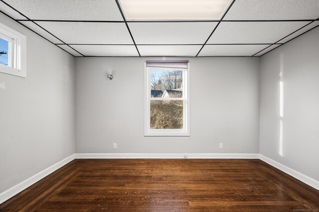 unfurnished room with dark hardwood / wood-style floors and a drop ceiling