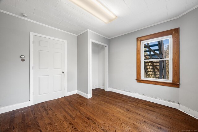 unfurnished bedroom with a closet, crown molding, and hardwood / wood-style floors