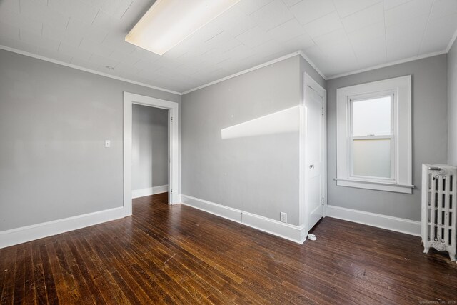 unfurnished room featuring crown molding, radiator heating unit, and dark hardwood / wood-style flooring