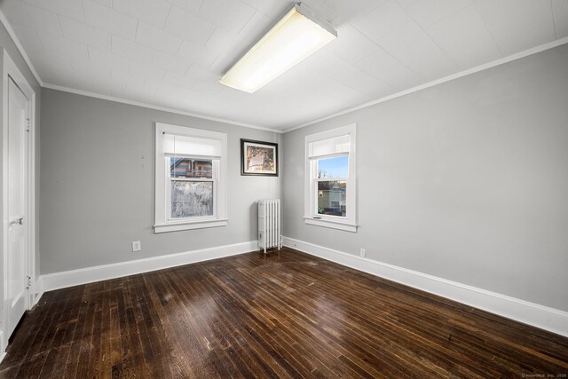 empty room featuring radiator, dark wood-type flooring, and ornamental molding