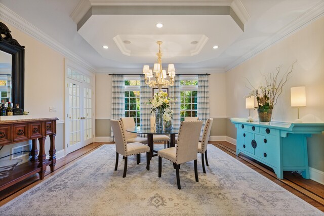 dining space with a raised ceiling, french doors, crown molding, and light hardwood / wood-style flooring