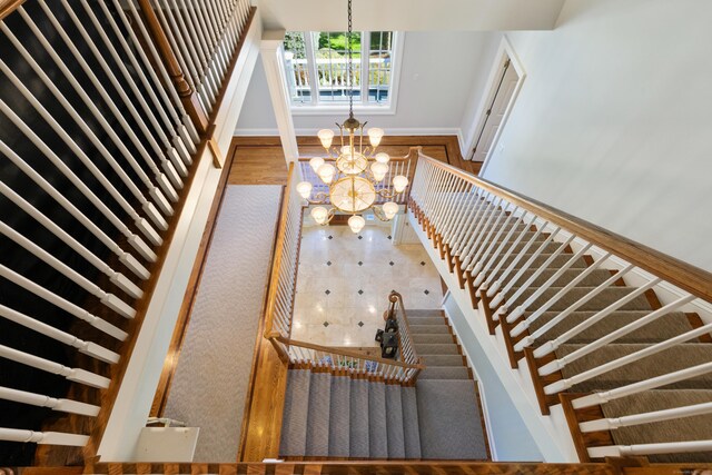 stairway with wood-type flooring and a notable chandelier